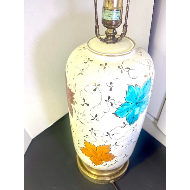 A charming 1950s table lamp with a cream-glazed ceramic body. It is hand-painted with large grape leaves in turquoise,...
