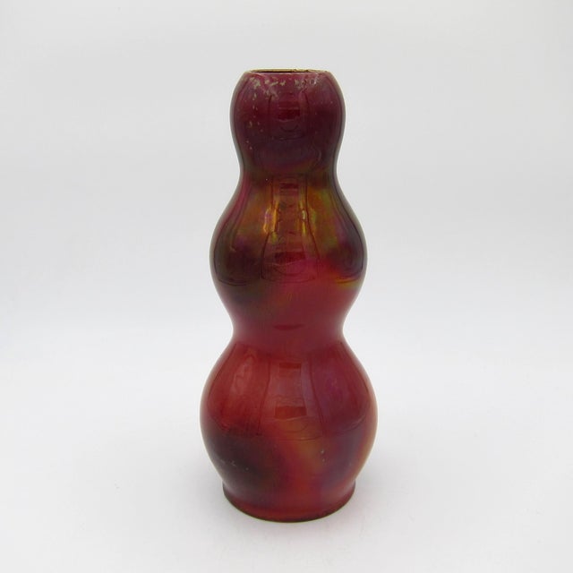 A dark red antique vase of triple gourd shape enveloped in a metallic lustreware glaze with areas of iridescence, creating...