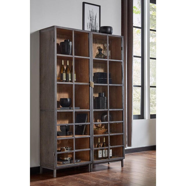 A 75-inch steel frame surrounds soft gray acacia, with one sculptural gunmetal handle running down the glazed door....