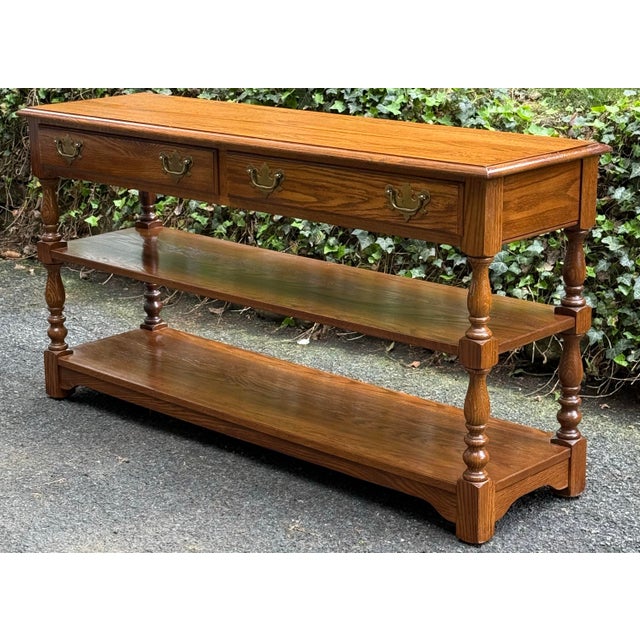 A late 20th century Pennsylvania House American Traditional solid oak console or sofa table having two drawers with brass...