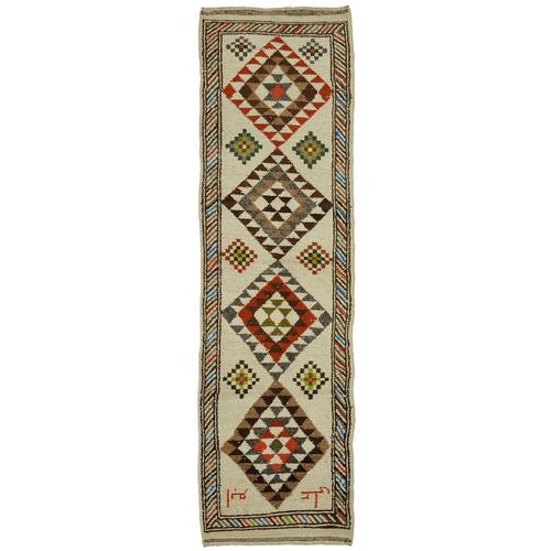 This exquisite runner rug is a rare example of tribal craftsmanship, hand-knotted by the women of the Herki tribe during...