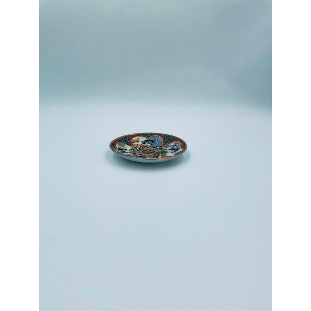 This teacup saucer, produced in Japan between the 1930s and 1950s in the opulent Satsuma, Kutania style, is made of high-...