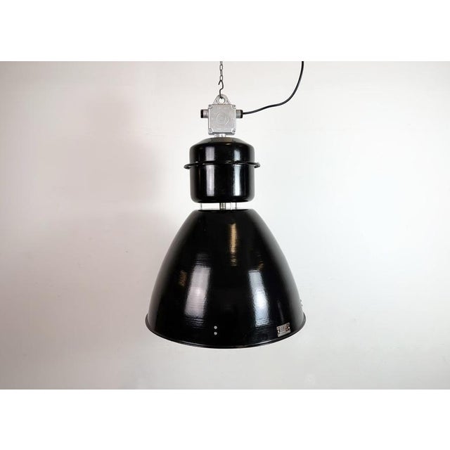 This large black industrial factory pendant light was designed and produced by elektrosvit in former czechoslovakia during...