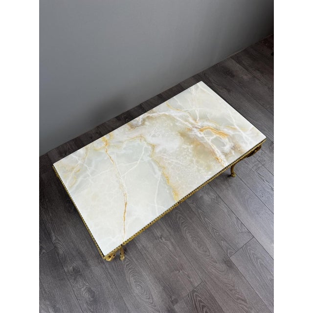 A superb gilt bronze coffee table, enhanced by an elegant, veined white marble top with a particularly decorative design....