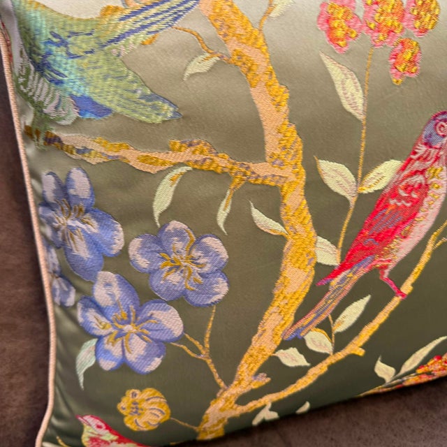 The composition places songbirds across a field of golden twisting branches, lavender iris, pink flower clusters, and red...