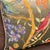 The composition places songbirds across a field of golden twisting branches, lavender iris, pink flower clusters, and red...