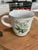The Vintage Noritake Stoneware mug in the "Mountain Flowers" pattern #8343 features the Avalanche Lily design in green....