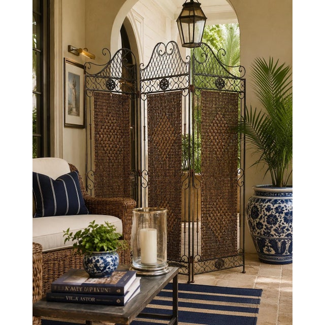 An elegant vintage three-panel folding room divider featuring a beautifully crafted wrought iron frame with decorative...