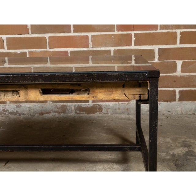 A contemporary coffee table made from an antique wooden fragment door with raised motifs under glass and mounted on a...