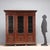 Neo-Renaissance-style walnut bookcase. Carved foliage and scrolls throughout, three glass doors with wrought iron grilles...