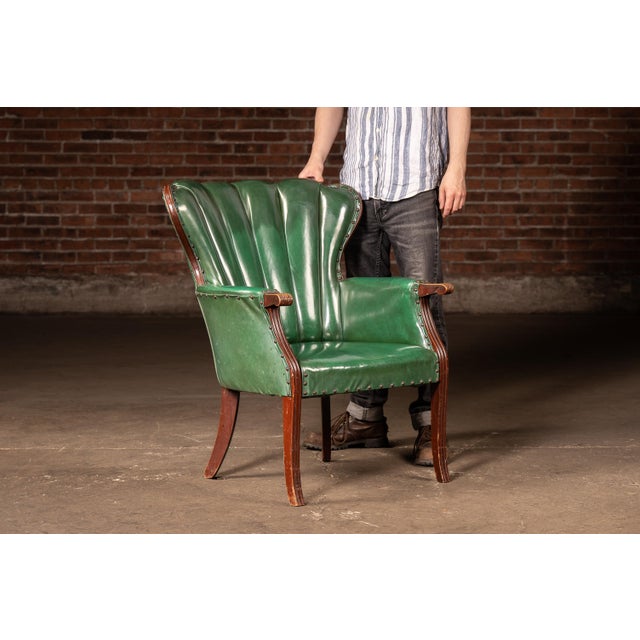 Art Deco influenced lounge or club chair featuring a dramatic fan-form shell back upholstered in deep green vinyl with...