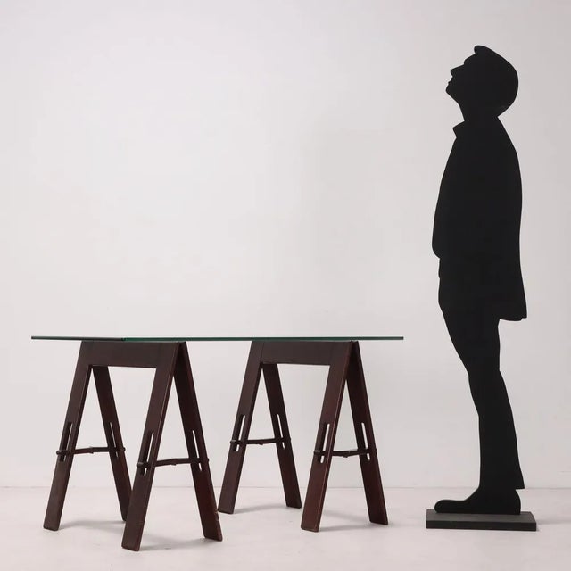 Vintage table with glass top and foldable wooden trestle legs. This piece is attributed to the mentioned designer/maker....