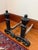 Pair of black wrought iron andirons. Each one has an urn finial on a square tapered post. Large scrolled feet sit at the...