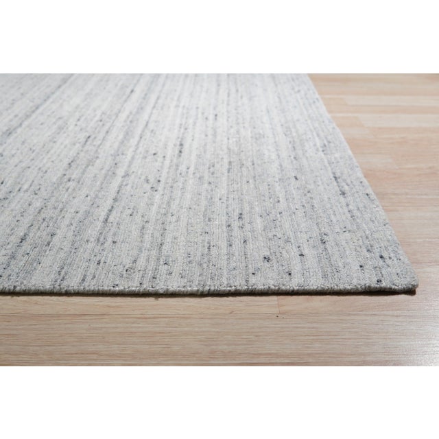 A hand-knotted wool rug, made in India and measuring 9' x 12'. Geometric drawing - repeating motifs held inside strong...