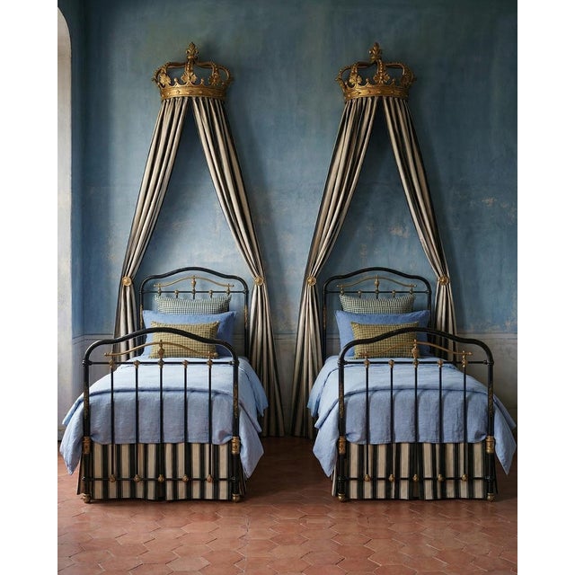 A matching pair of antique iron single beds from circa 1880, elegantly finished in black with intricate cast iron details....