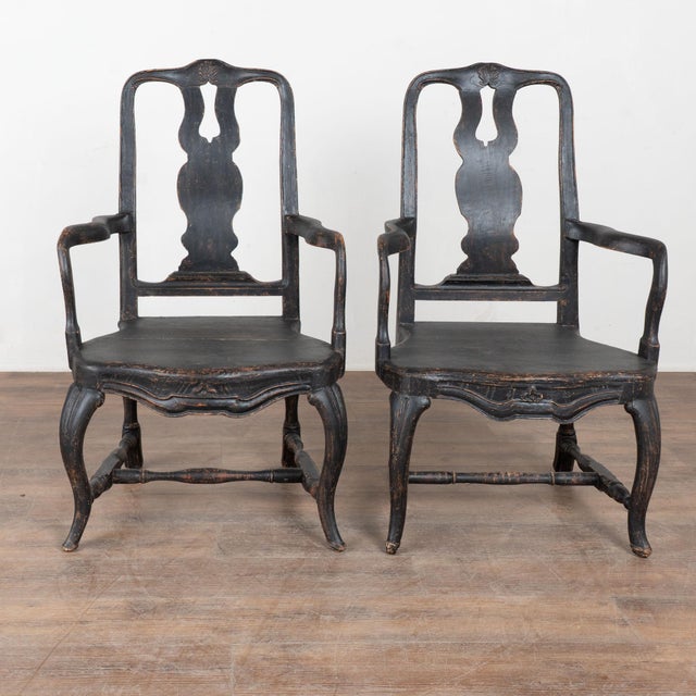 Pair of 19th century Swedish armchairs crafted in pine. The chairs feature a newer black painted finish, distressed to...
