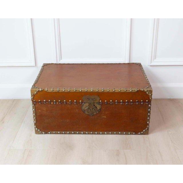 Made in France in the nineteenth century, this rectangular trunk is covered in patinated leather and decorated with rich...