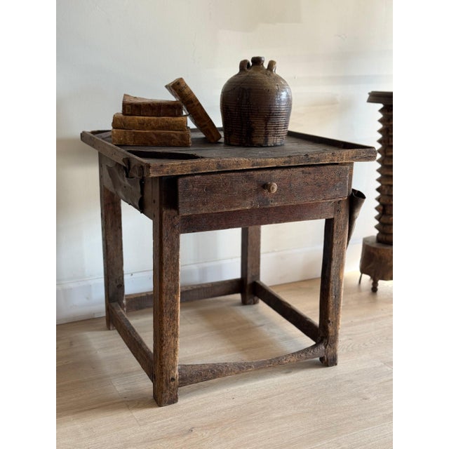 A primitive French cobbler's bench worn nearly black from a century of work, the plank top scarred and waxed deep, with a...