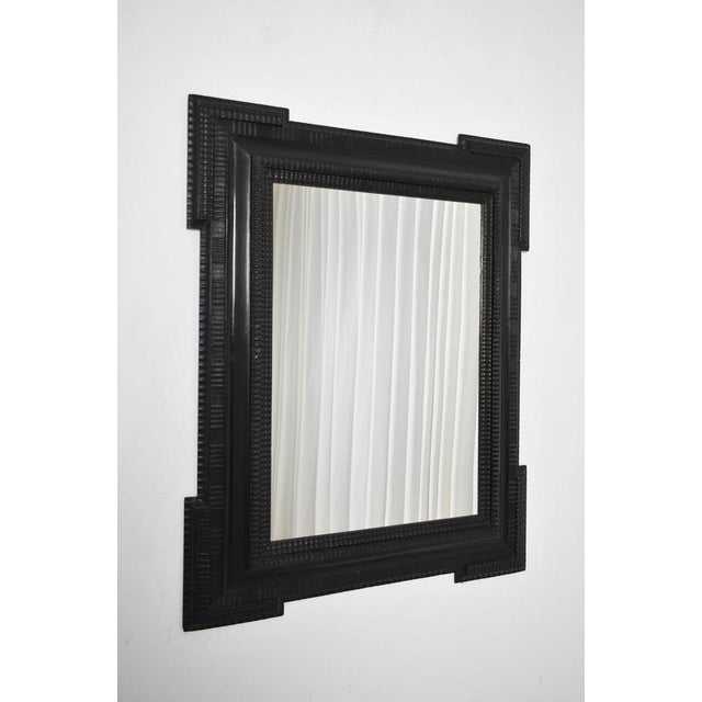 Carved ebonised wooden mirror, XIXth c. Reverse profile mirror carved ebonised wood mirror. Italy, 19th c. Height: 101 cm...