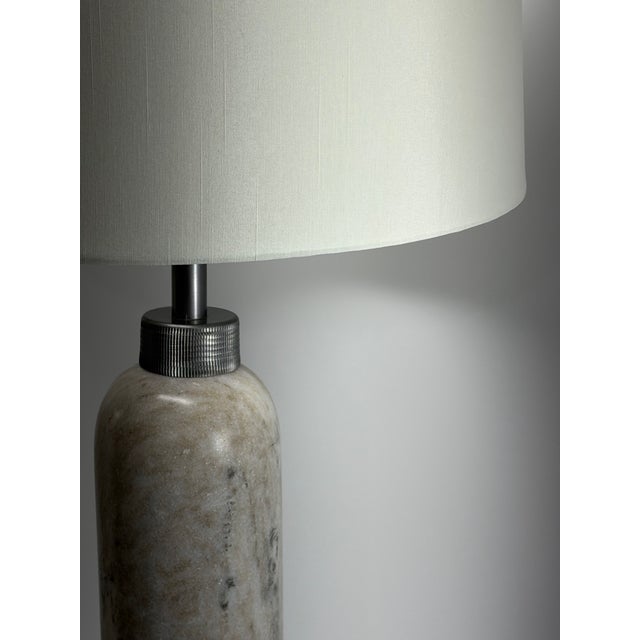 A sophisticated pair of substantial column table lamps crafted from natural cream marble with soft taupe and charcoal...