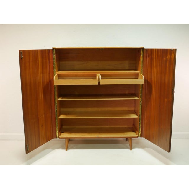 Elegant vintage hall cabinet from the 1960s with high-quality walnut and makoré veneer. The warm wood tones, polished...