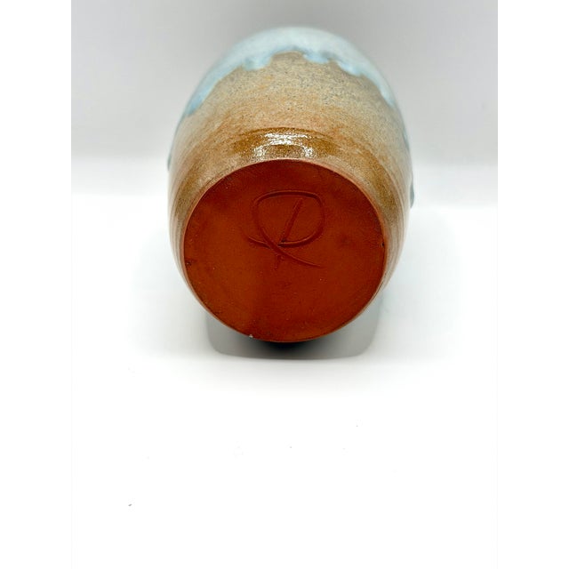 A beautiful artist signed studio pottery bud vase with a soft blue drip glaze over an earthy brown stoneware base. The...
