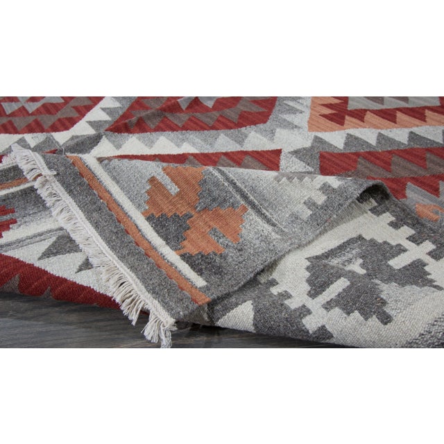 Beautiful Modern Kilim Hand-knotted wool rug with a red, gray, and peach field in-all-over geometric design. This rug...