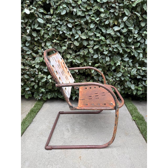 Mid-20th century cantilever patio chair featuring a sculptural pressed steel shell seat and tubular steel frame. The form...