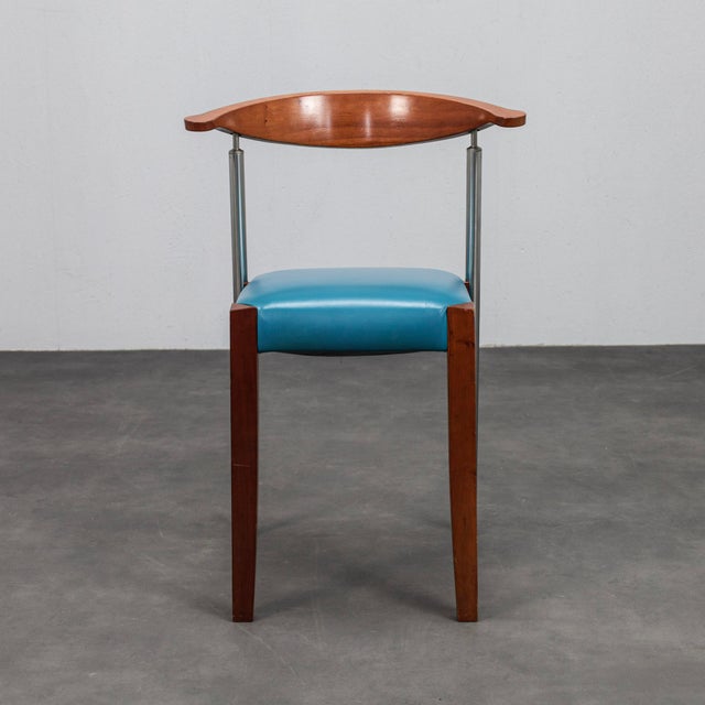 A striking set of four italian postmodern dining chairs combining warm cherrywood, stainless steel and vibrant blue...