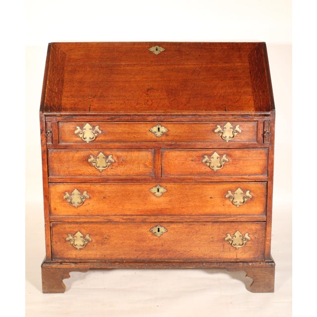 George III oak slant top desk, early 19th century. With a hinged slant top, interior of desk with central prospect door...