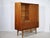 Teak highboard with a glass display case, sliding door, and delicate base. The glass display case with two glass shelves...