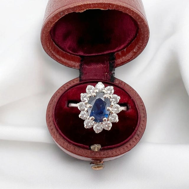 Vintage daisy ring (circa 1960) in 18 carat white gold (750 thousandths). It is adorned with a natural blue sapphire of...