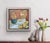 This artwork presents a still life composition featuring a tipped-over vessel and scattered yellow flowers, creating a...