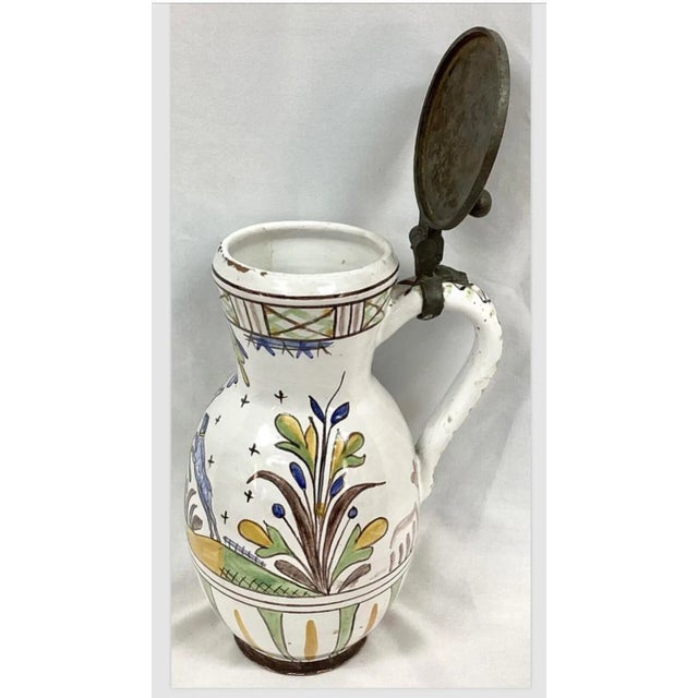 German Faience pitcher/jug with hinged pewter lid and handle. Hand painted floral design, along with stag and dog, on...