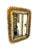 A striking vintage sunburst mirror featuring a sculptural gilt metal frame with radiating leaf-like details that create a...