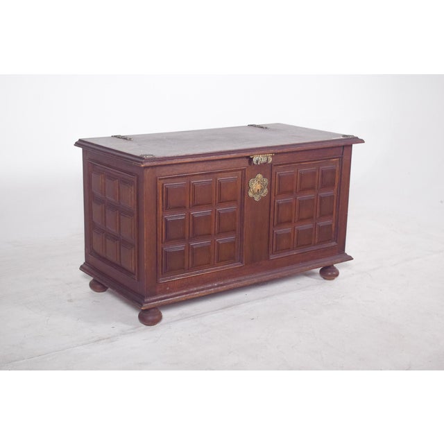 Dark wood chest with checkered cushioning. The front is decorated with embossed panels organized in a checkerboard...