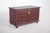 Dark wood chest with checkered cushioning. The front is decorated with embossed panels organized in a checkerboard...