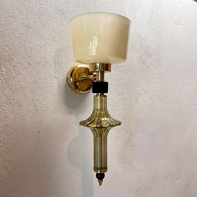 Pair of mid century modern Murano glass sconces, Italy 1990s. The Italian sconces are made of polished brass mounts and...