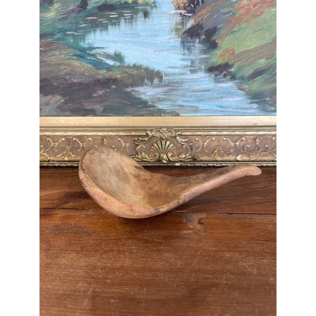 This 19th-century hand-carved wooden ladle is a striking example of early utilitarian craftsmanship, likely originating...