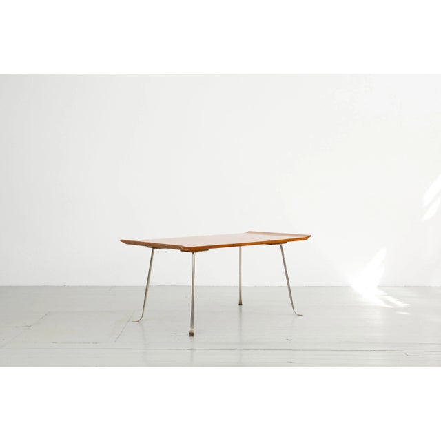 This side table was designed in Germany in the 1950s. It features a table top bent up at the ends with inlaid stripes. The...