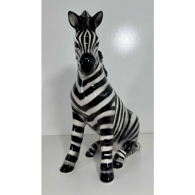 Elegant seated zebra sculpture, produced in Bassano del Grappa, Italy. Hand-decorated in glazed ceramic, it features...