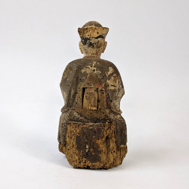 This wooden official used to be fully painted in vibrant colors, that is now faded away with time.