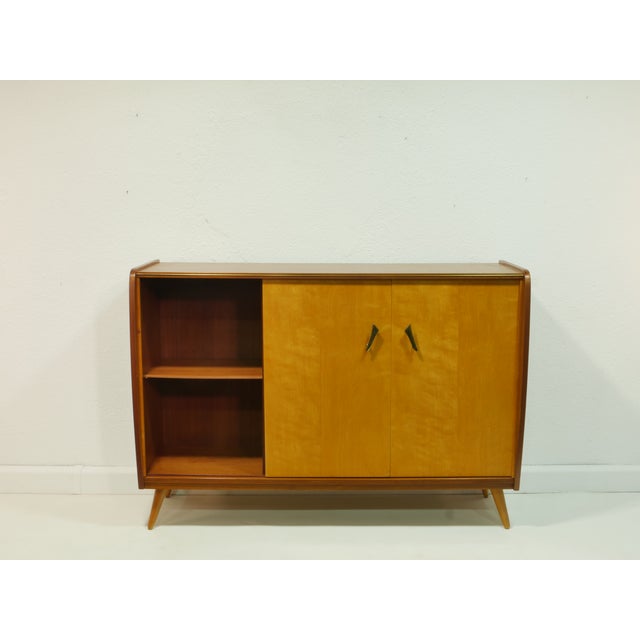 This vintage sideboard from the 1960s is an original German design piece and impresses with its elegant design. The...