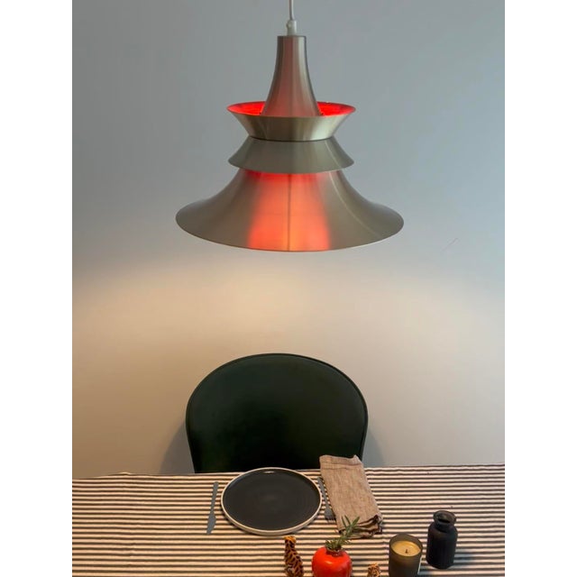 When lit, a warm red glow emanates from within the nested inner shades. Attributed to Bent Nordsted, the lamp's...