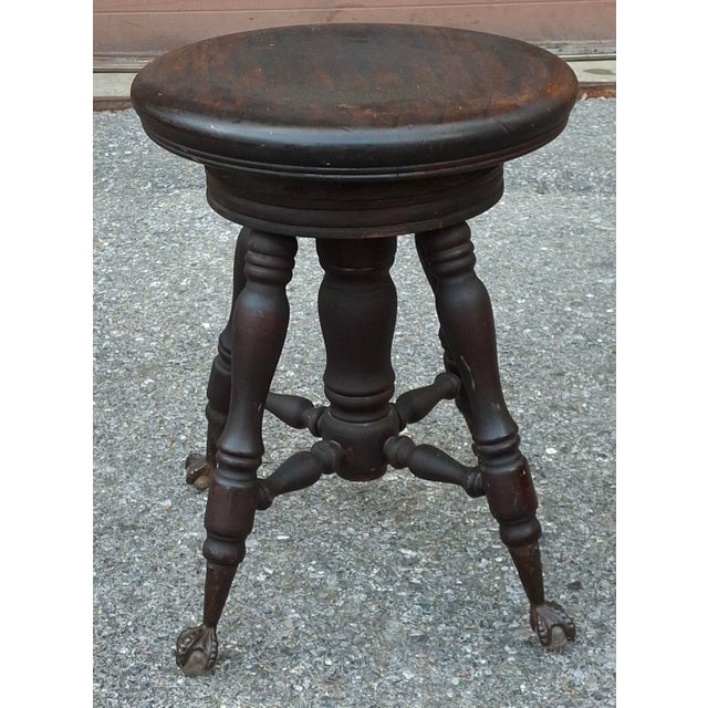 A the late 19th/early 20th century piano stoll featuring a circular wooden seat that spins to adjust height. Features four...