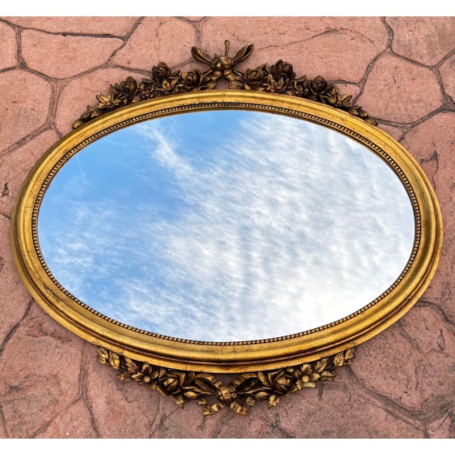 An ornate mirror reflecting the Louis XVI style, popular in France during the 18th century and continued to be reproduced...