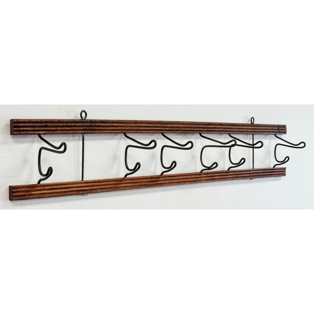 Antique primitive wall hook featuring carved wood top and bottom framing to support six (6) double cast iron hooks. Each...
