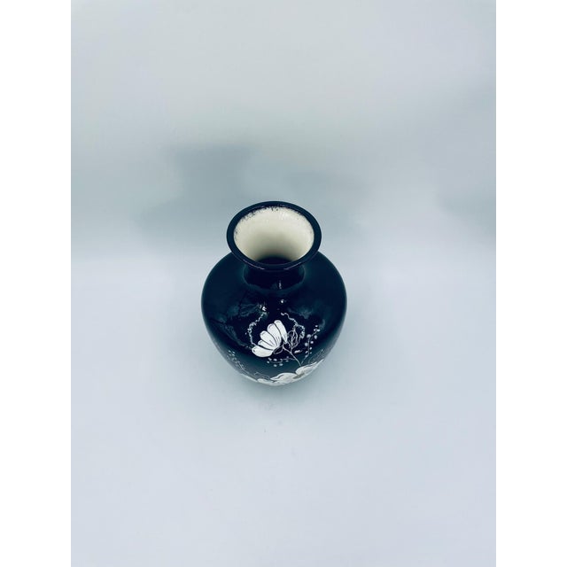 A decorative Art Deco vase made of high-quality ceramic. The black vase features an elegant, rounded shape with a tapering...