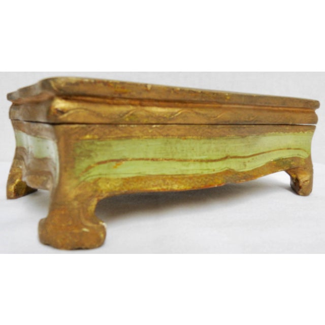 The curved lines on the edges of this box lend a graceful air to the box perched on curved feet. Details have been carved...