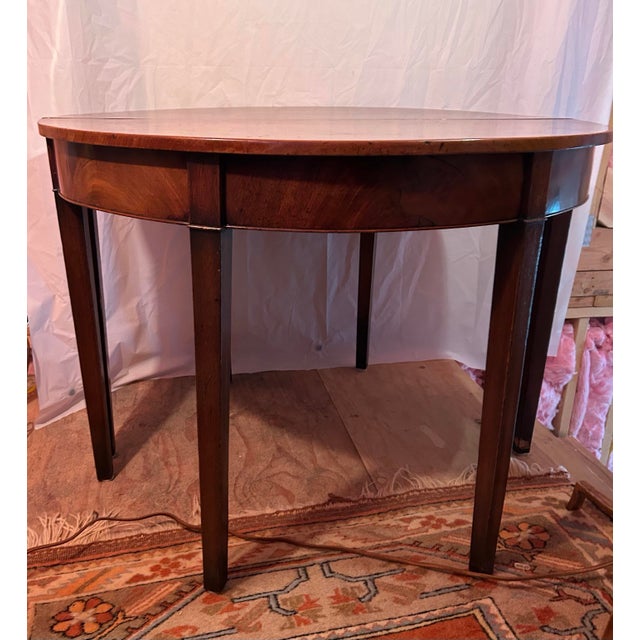 Elegant pair of Federal-style demi-lune console tables crafted in mahogany veneer with refined neoclassical proportions....